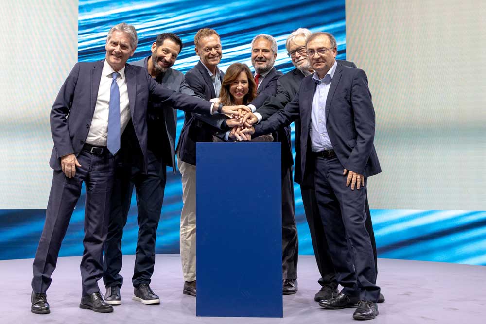Seven people standing in front of a podium, pressing a button together