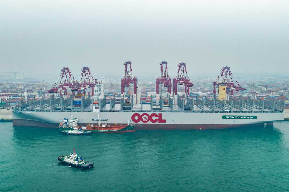 Container ship and bunker vessel in front of harbour cranes in Qingdao