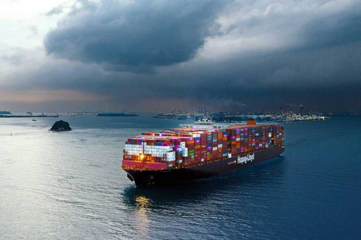A container ship off a harbour, with a thunderstorm in the background