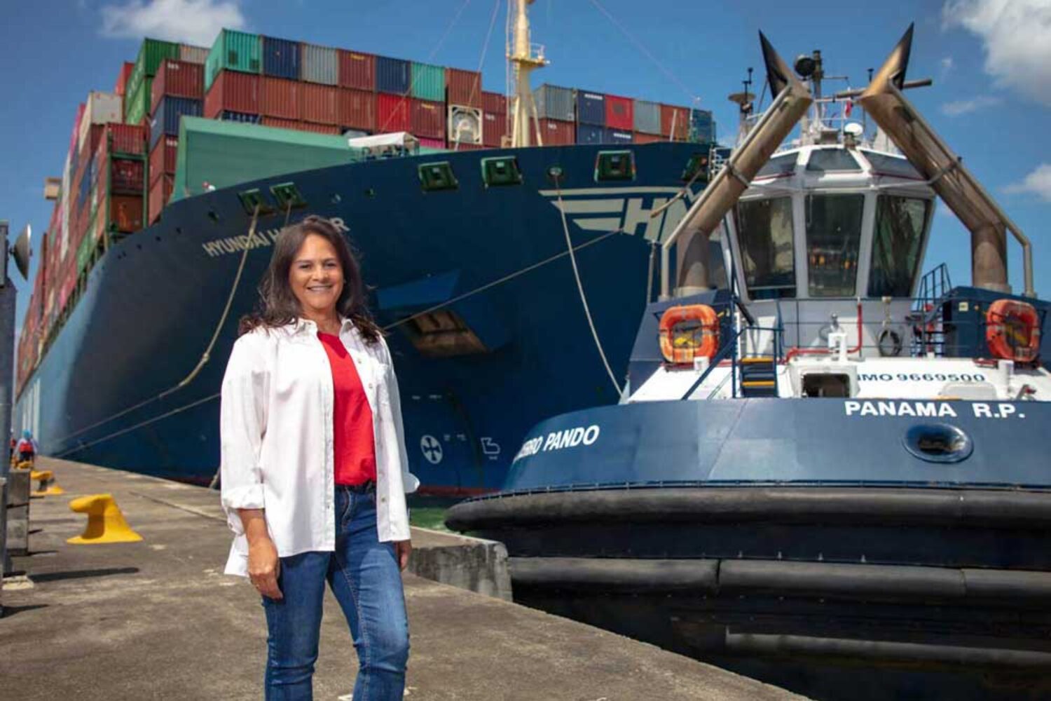 Ilya Espino de Marotta, Administrator of the Panama Canal Authority, in front of a tugboat and a container ship