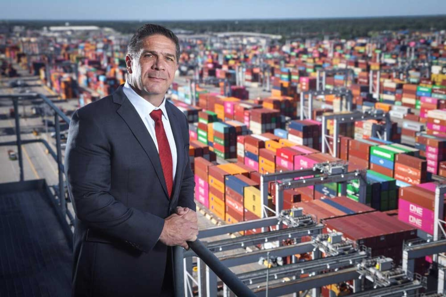 Picture of a man in a suit standing in front of some containers