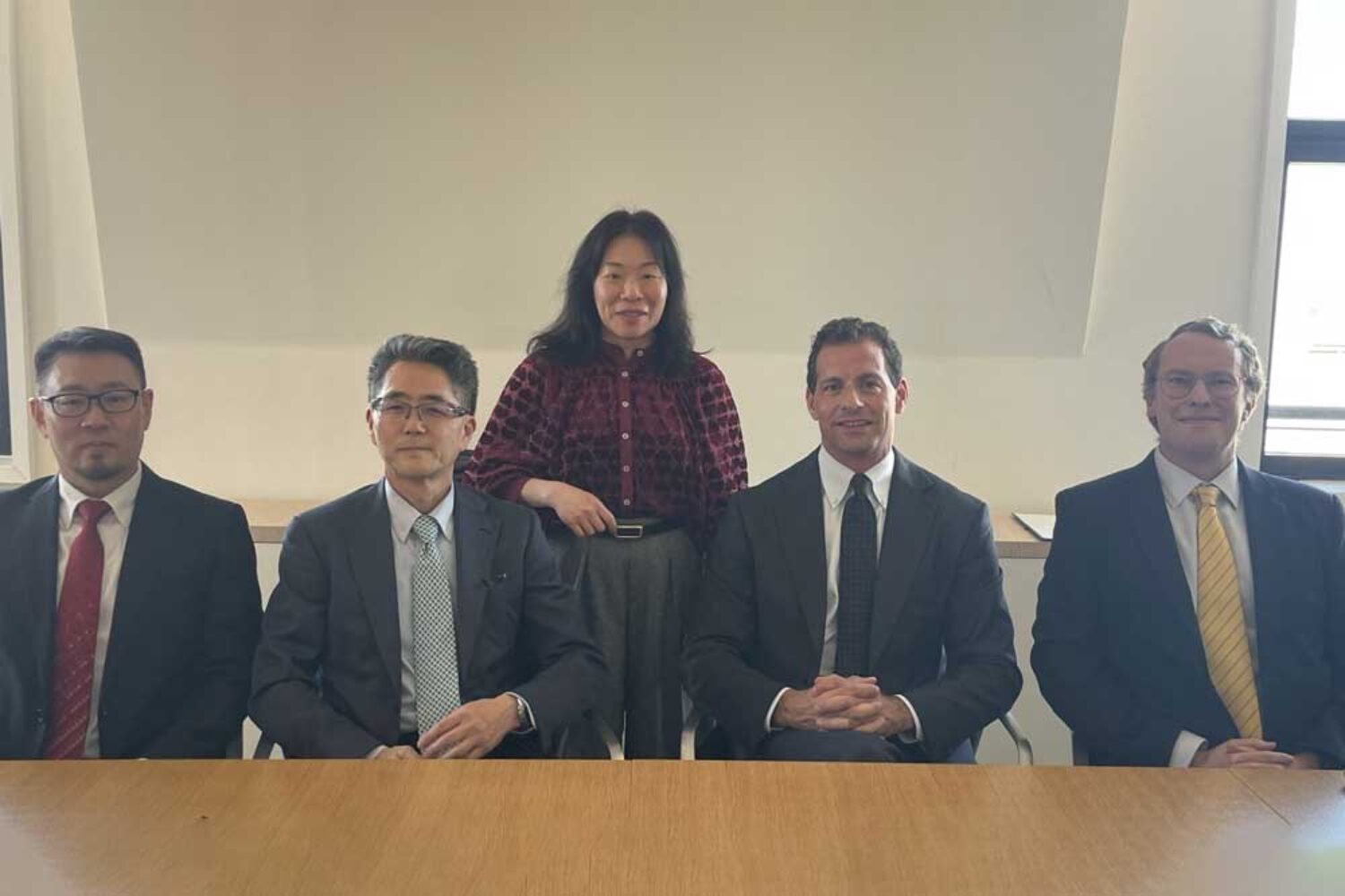 Members of MOL and V.Group, four men in suits at a desk, a woman standing behind them