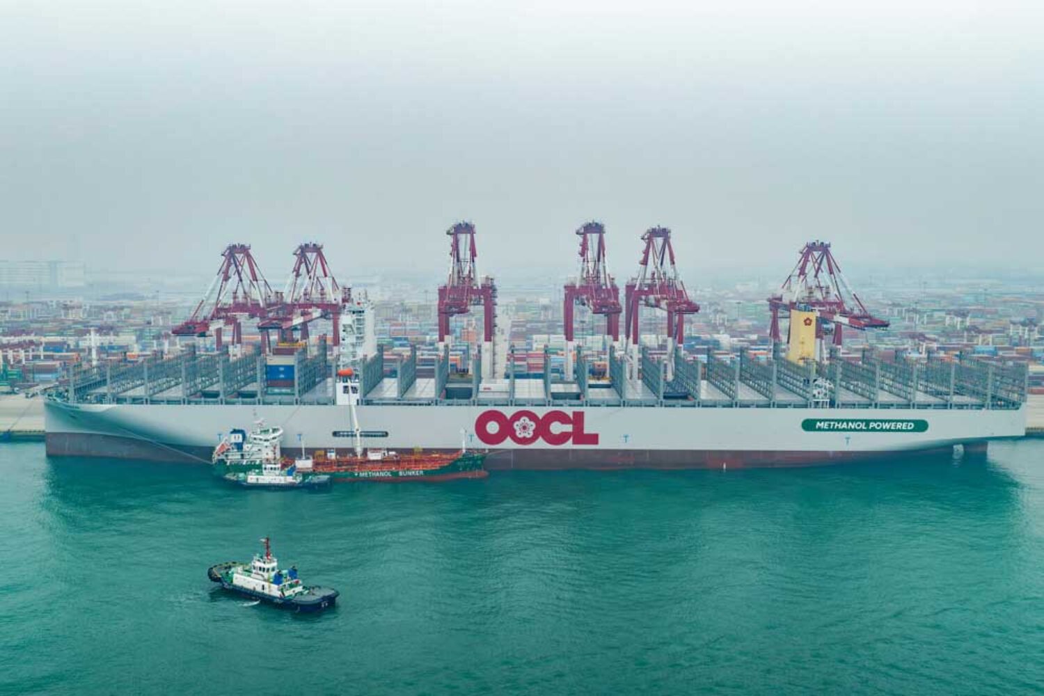 Container ship and bunker vessel in front of harbour cranes in Qingdao